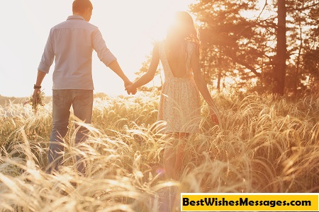 lovers walking in a field at sunset holding hands
